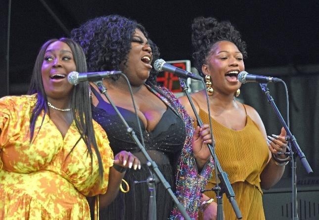Three vocalists singing together on the festival stage