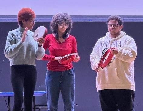 Fabiola Méndez making music with two students holding percussion instruments